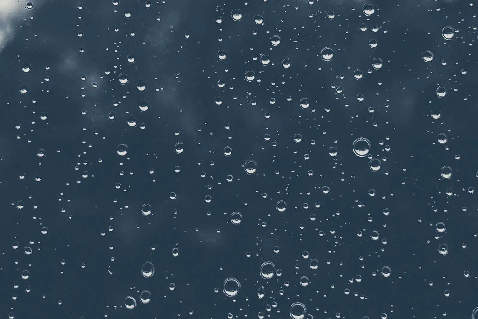 Rain drops on a window, in muted navy tones